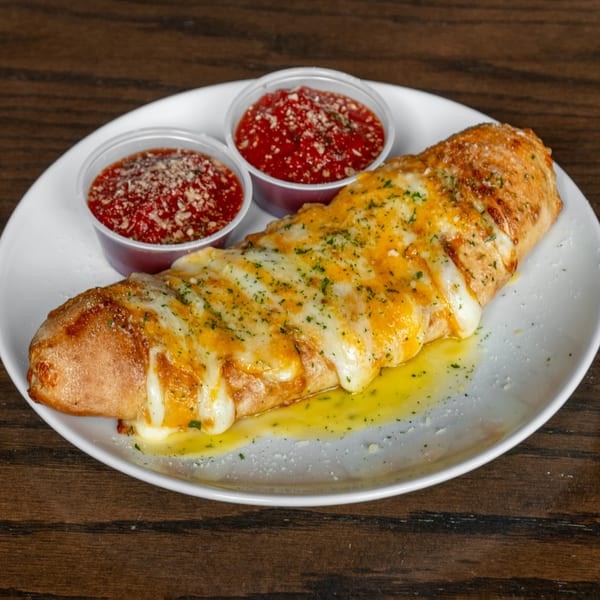Golden-brown calzone topped with melted cheese and herbs, served with two cups of marinara sauce.