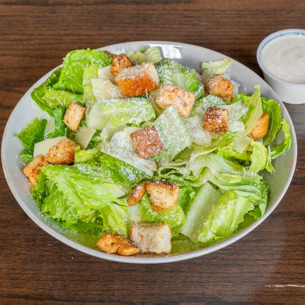 A fresh Caesar salad with crisp romaine lettuce, croutons, and grated Parmesan cheese.